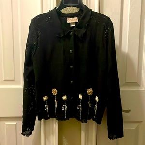 Black, loose knit sweater with heart buttons and small, crocheted flowers.